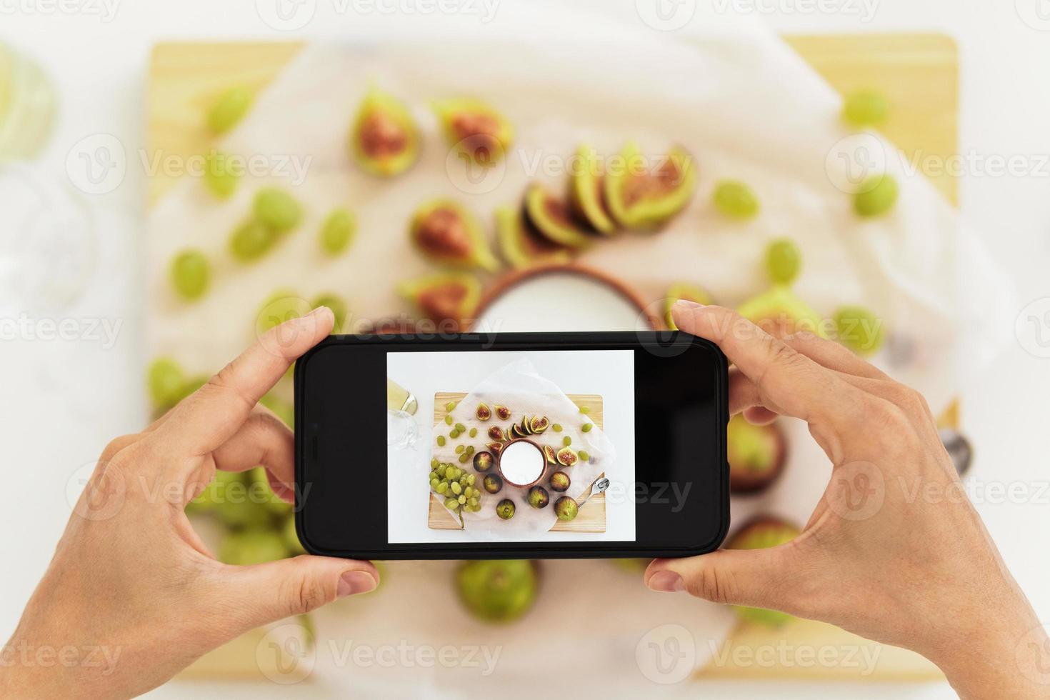 vrouw nemen foto van haar heerlijk Grieks yoghurt met vijgen door haar smartphone