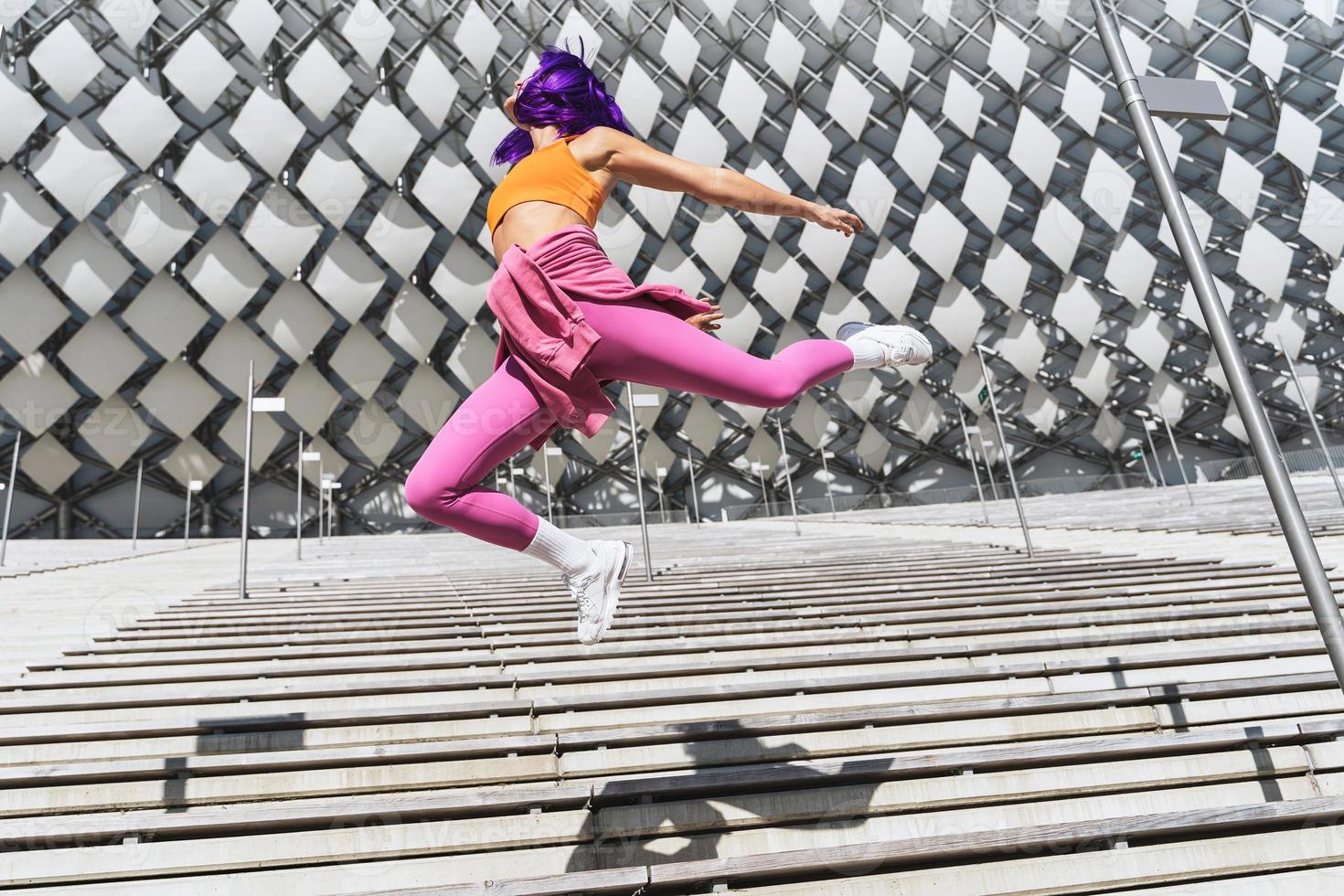 zorgeloos vrouw vervelend kleurrijk sportkleding jumping Aan de straat gedurende zomer dag foto