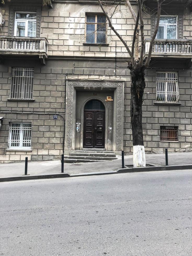 oud oude antiek mooi gesneden houten deur Aan de veranda van een steen historisch gebouw met balkons en ramen Aan de weg geneigd zijn 45 graden foto