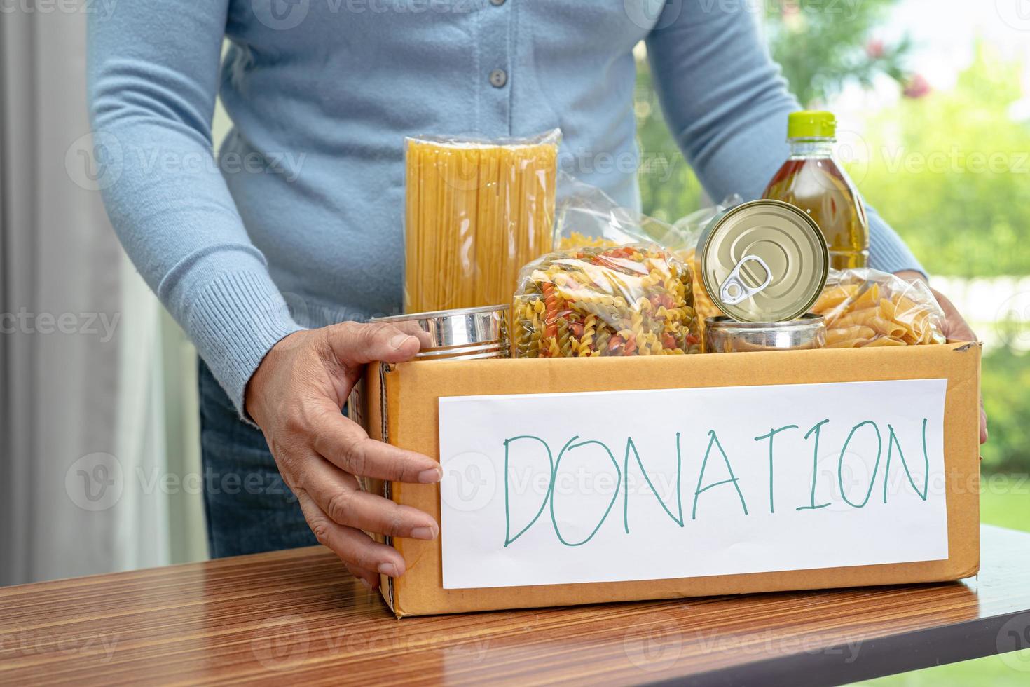 vrijwilligers die verschillende soorten droog voedsel in de donatiebox stoppen om mensen te helpen. foto