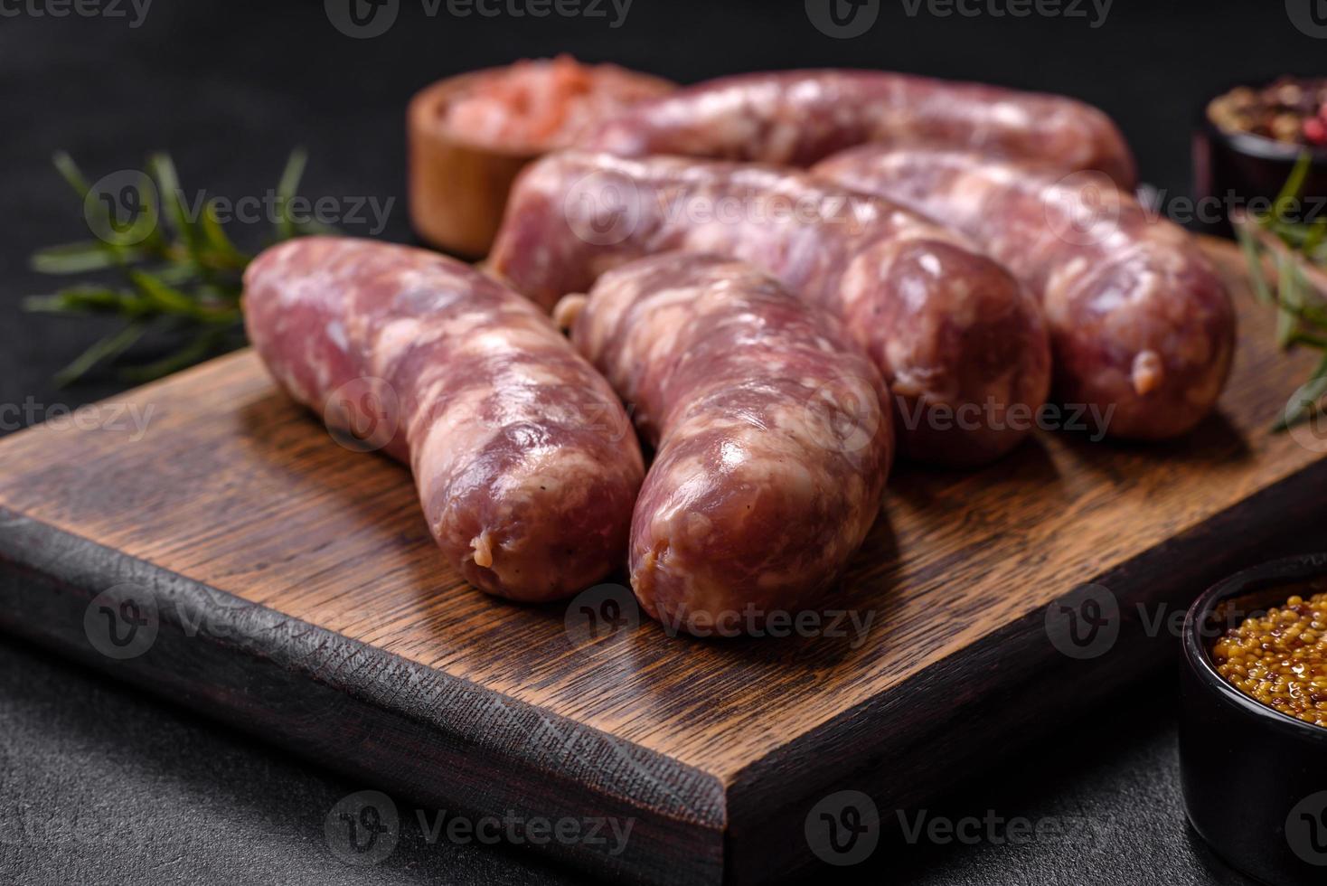 rauw varkensvlees worstjes rooster met specerijen en kruiden Aan een donker beton tafel foto