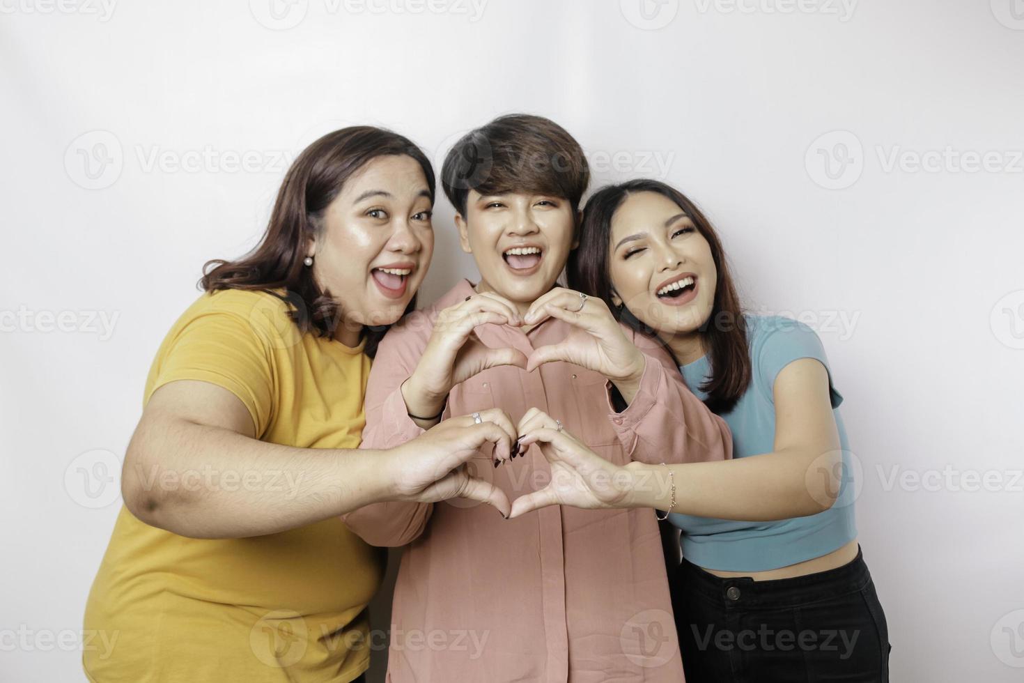 drie Aziatisch Dames voelen gelukkig en een romantisch vormen hart gebaar drukt uit inschrijving gevoelens, dichtbij vriendschap concept. foto