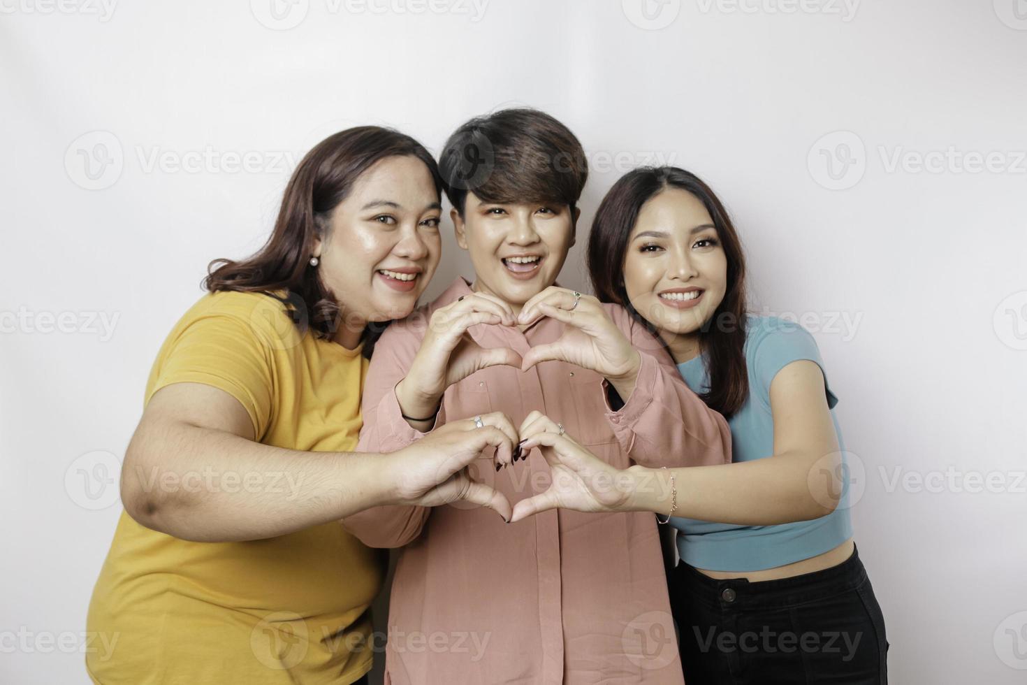 drie Aziatisch Dames voelen gelukkig en een romantisch vormen hart gebaar drukt uit inschrijving gevoelens, dichtbij vriendschap concept. foto