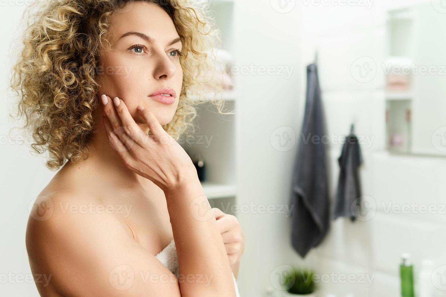 mooi vrouw met gekruld haar- na een douche in een badkamer foto