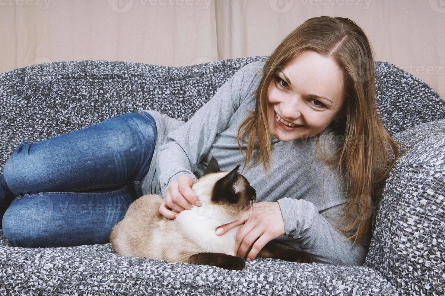 gelukkig jong vrouw ontspannende Aan bankstel met kat foto