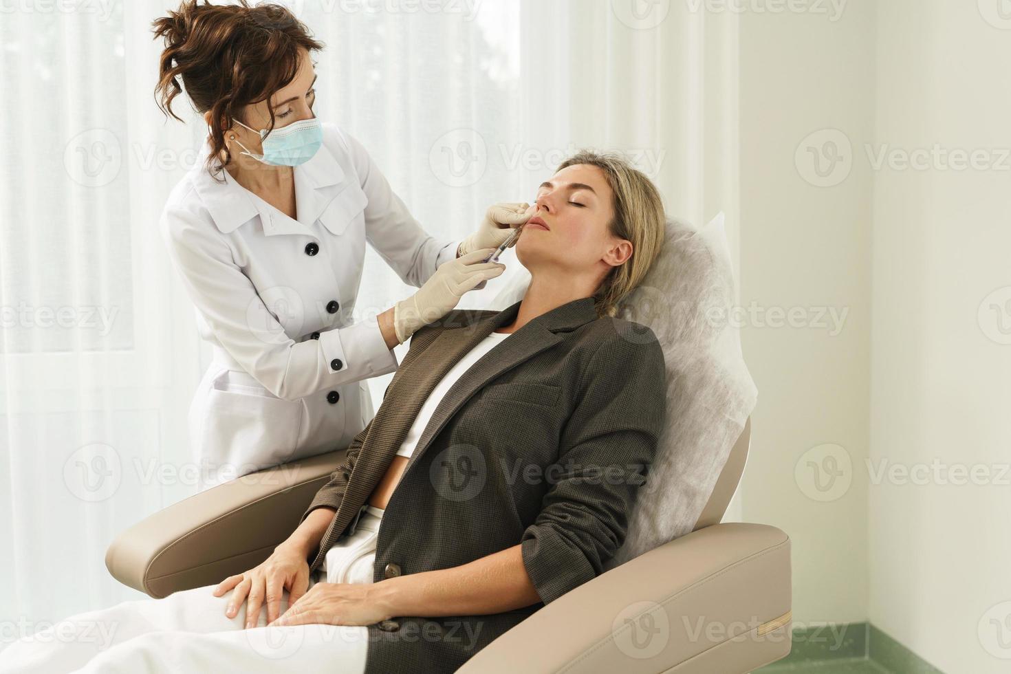 dokter en cliënt gedurende lip vergroting vulmiddel injecties in esthetisch medisch kliniek foto