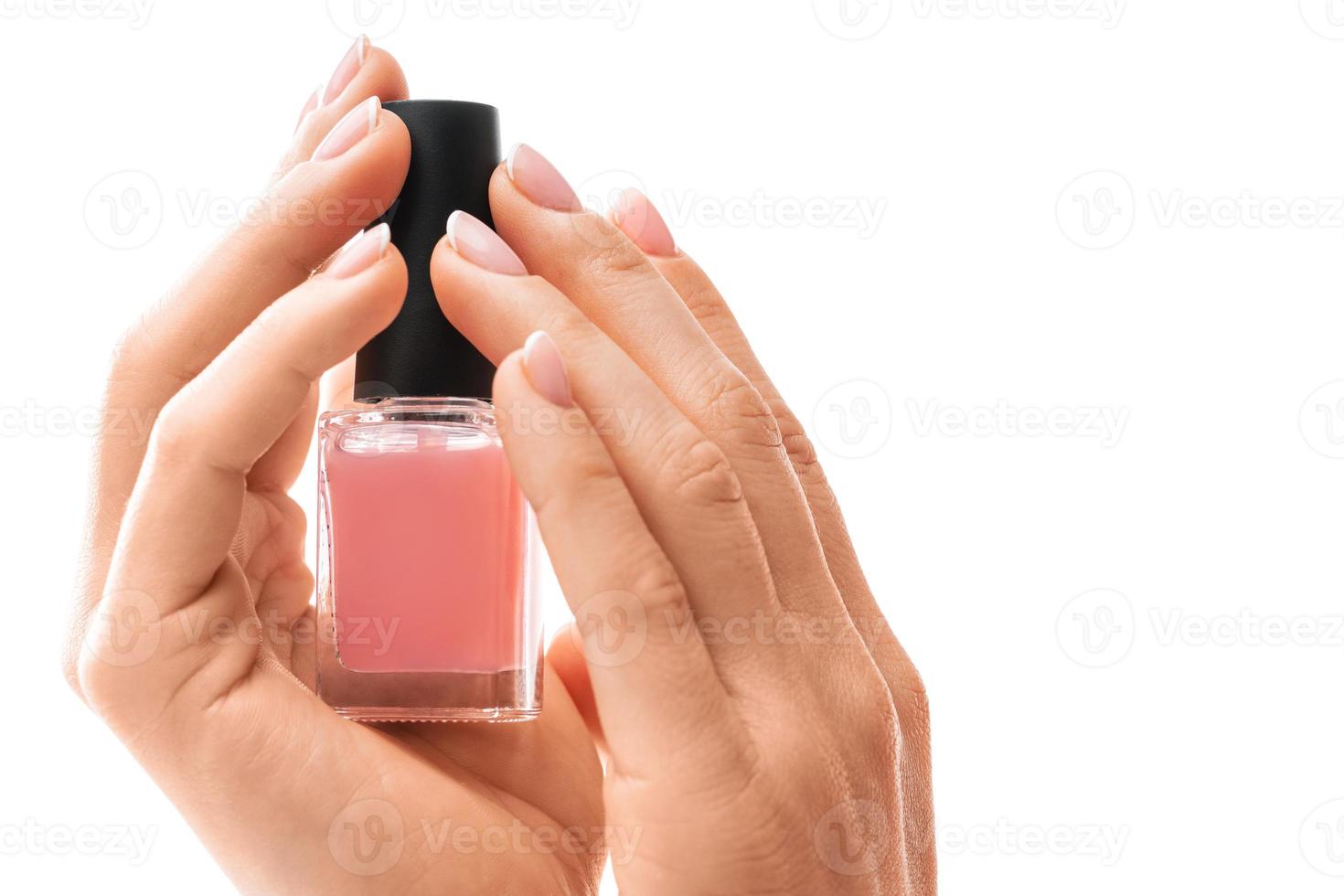 vrouw handen met mooi Frans manicure Holding fles van roze nagel Pools tegen wit achtergrond foto