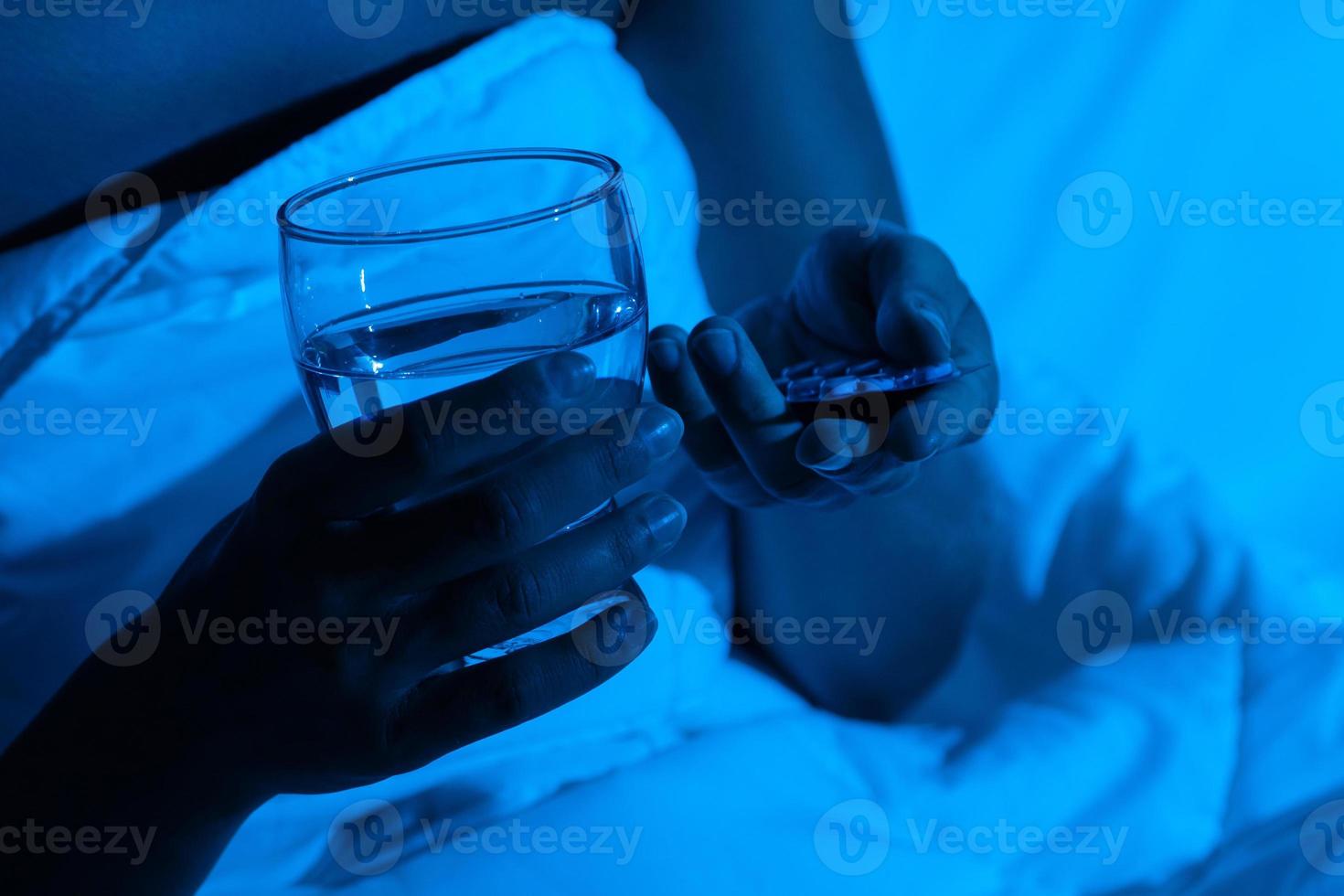 vrouw handen met een glas van water en slapen pillen foto