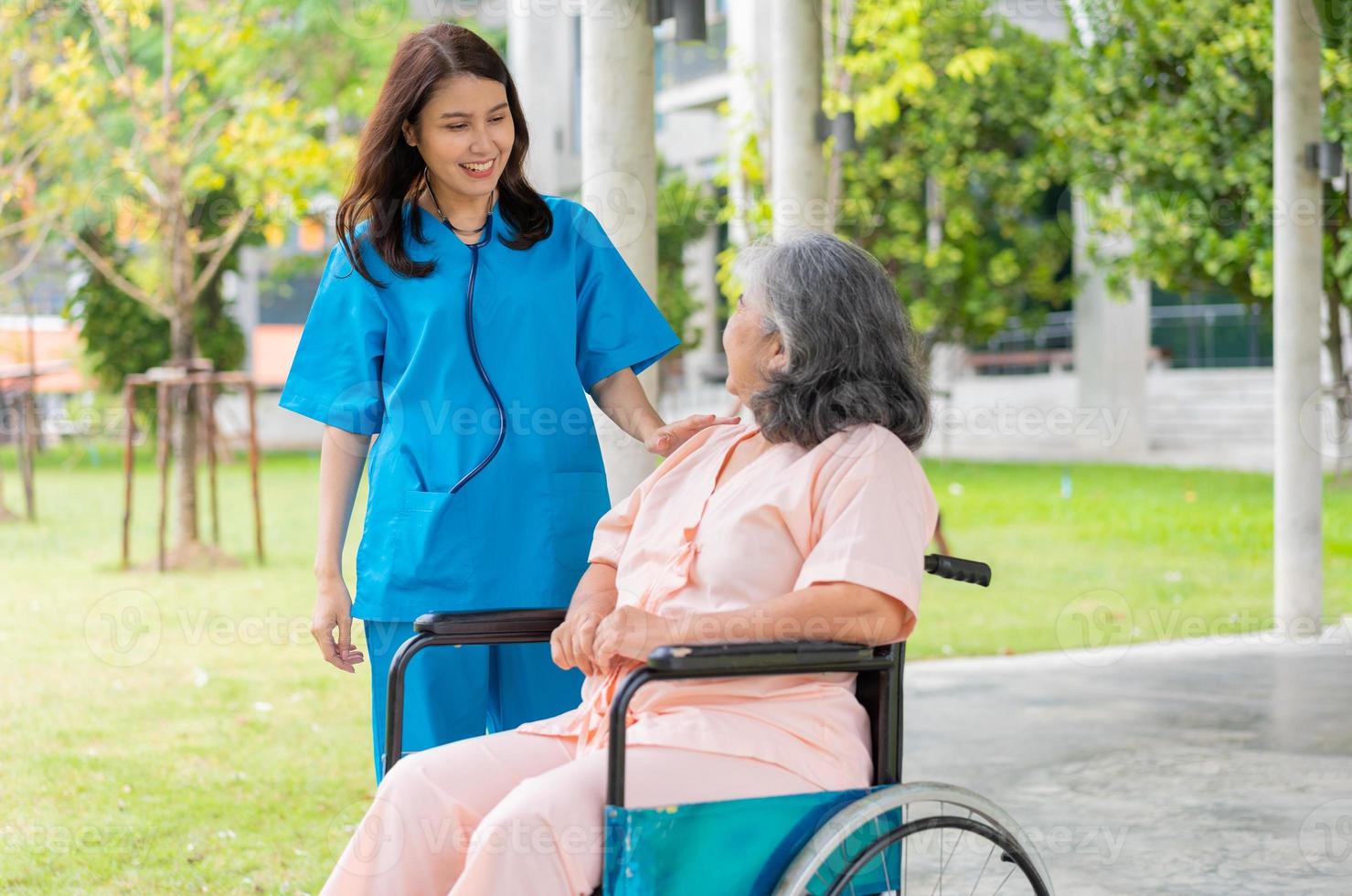 Aziatische zorgvuldige verzorger of verpleegster houdt de hand van de patiënt vast en moedigt de patiënt in een rolstoel aan. concept van gelukkig pensioen met zorg van een verzorger en spaar- en senior ziektekostenverzekering. foto