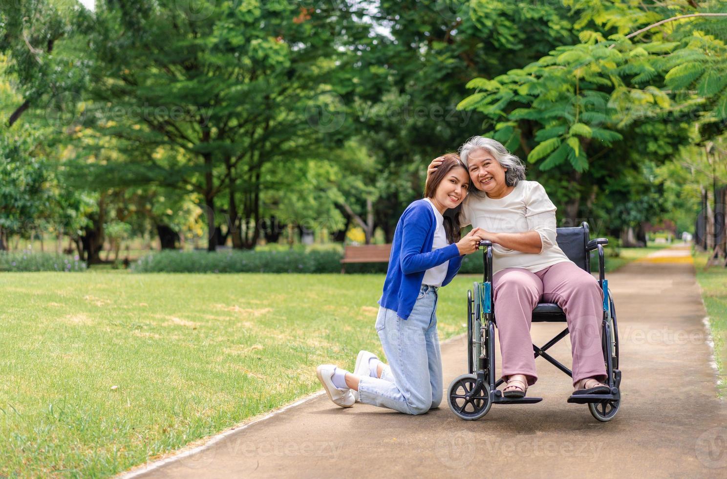 Aziatische zorgvuldige verzorger of verpleegster die voor de patiënt in een rolstoel zorgt. concept van gelukkig pensioen met zorg van een verzorger en spaar- en senior ziektekostenverzekering, een gelukkig gezin foto