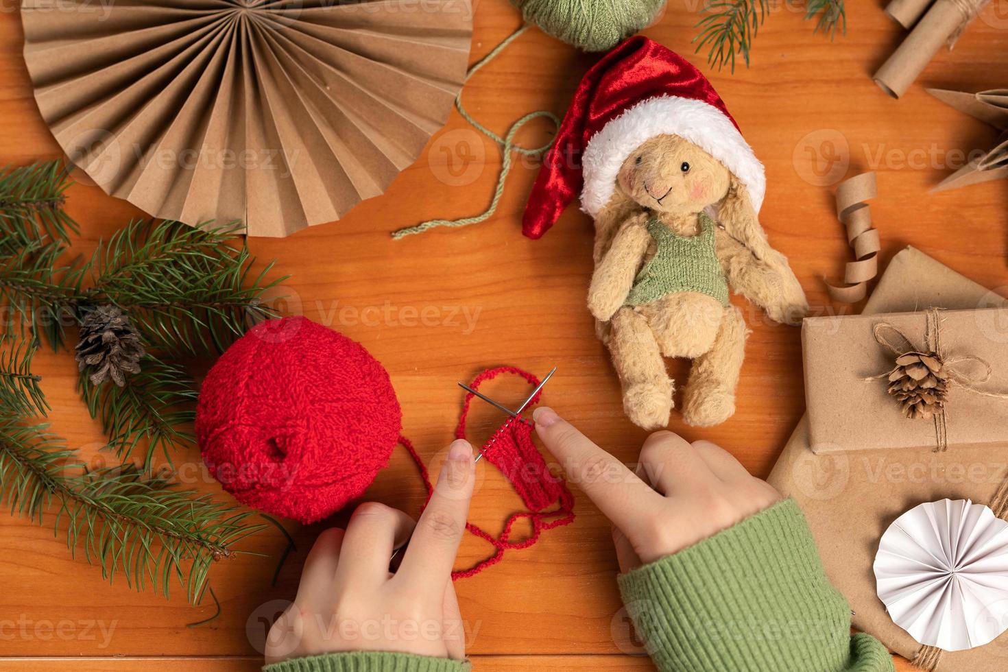 vrouw handen breiwerk een sjaal voor een speelgoed- konijn gemaakt in teddy techniek. handgemaakt speelgoed- en kleren voor het. foto