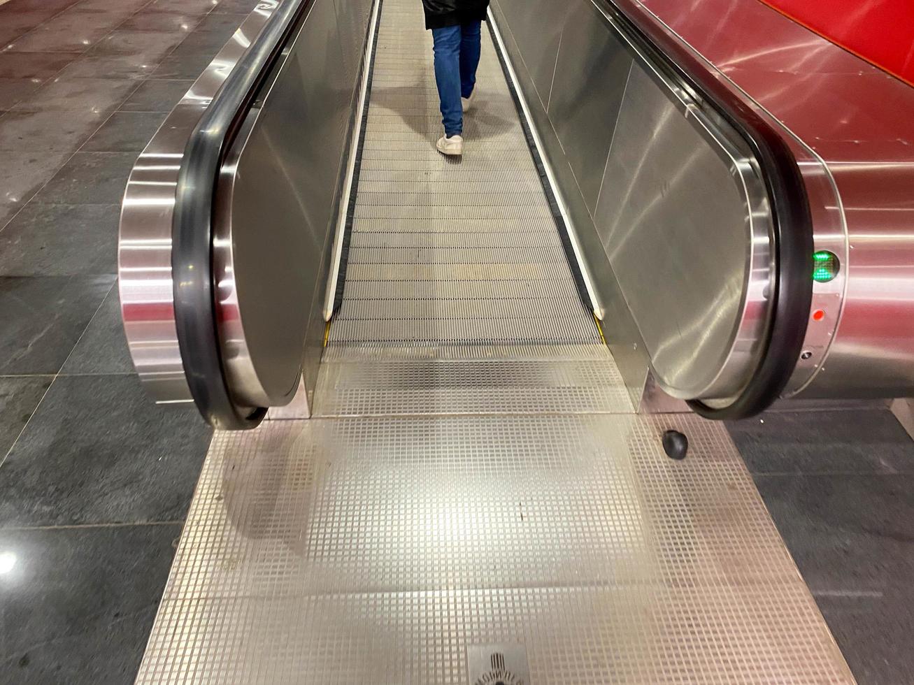 groot rood modern lang helder ondergronds loopbrug tussen metro stations met reizen wandelaars en roltrappen voor snel passage van passagiers foto
