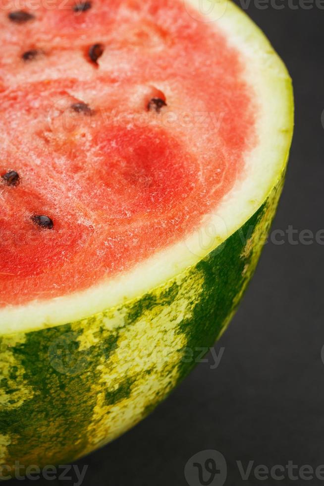 voor de helft van smakelijk en rijp rood watermeloen Aan een zwart achtergrond, structuur van sappig pulp van rijp rood watermeloen met zaden foto