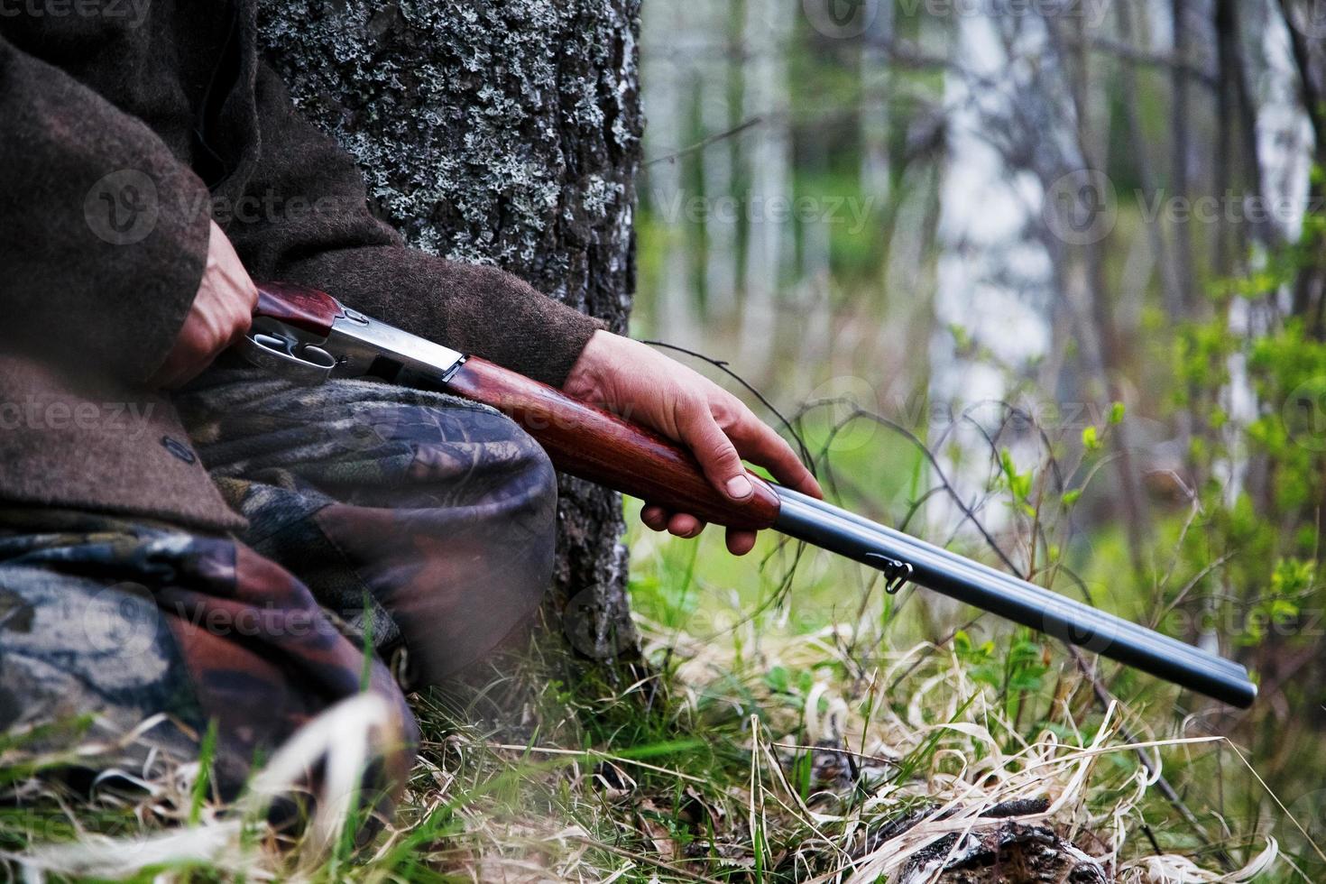 jachtgeweer detailopname in de handen van een jager zittend in wacht. aan het wachten voor spel foto