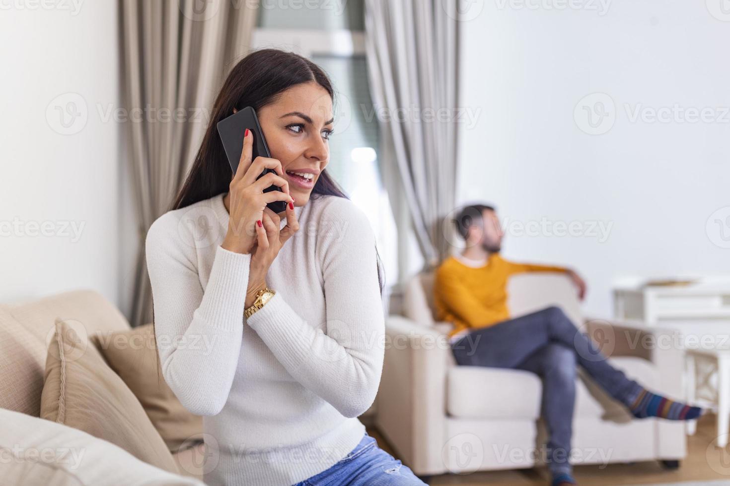 vrouw draaide zich om haar terug naar Mens, pratend Aan telefoon met haar minnaar, vriendje zittend in de terug aan het kijken TV. bedrog en ontrouw concept foto