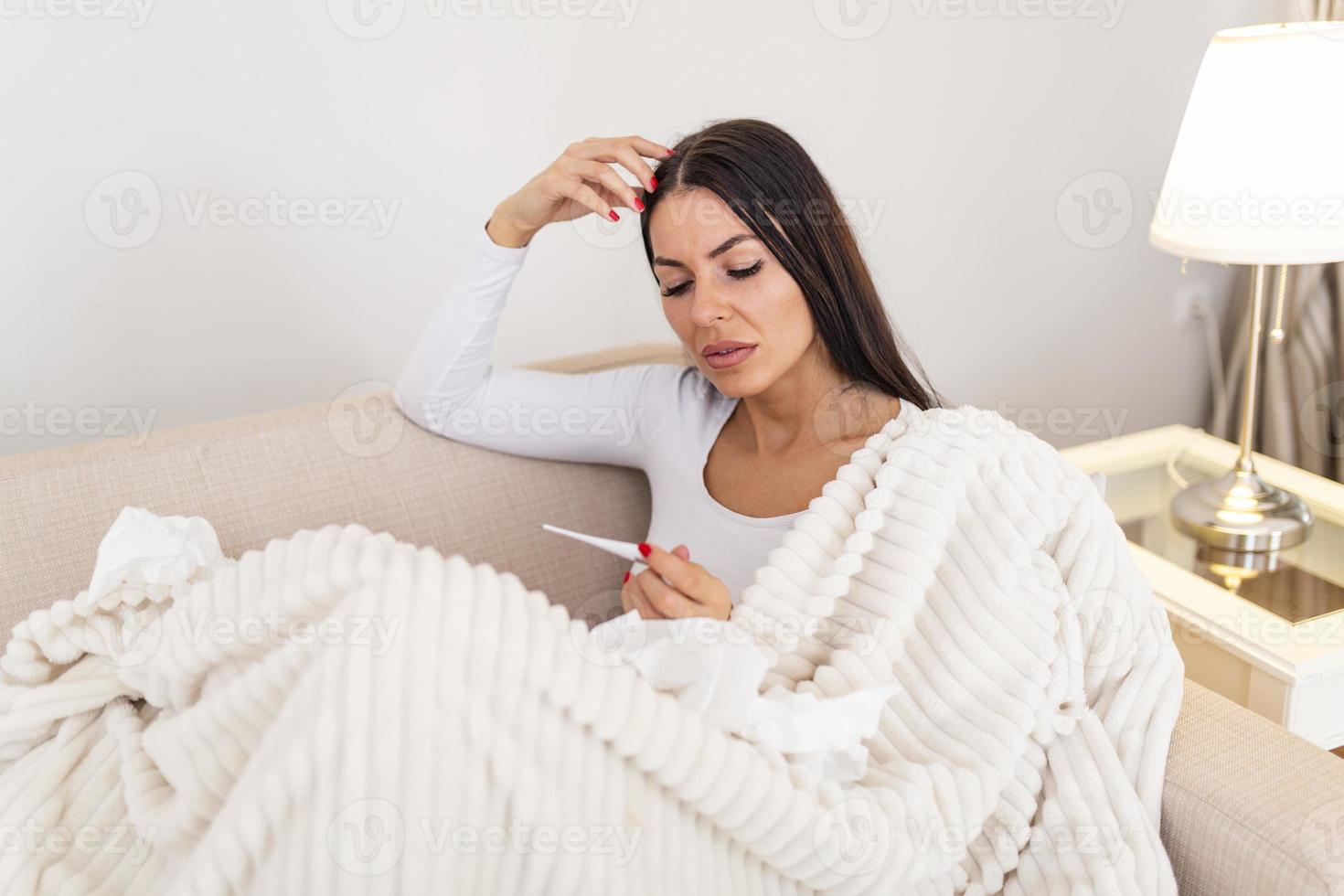 ziek vrouw met hoofdpijn zittend onder de deken. ziek vrouw met seizoensgebonden infecties, griep, allergie aan het liegen in bed. ziek vrouw gedekt met een deken aan het liegen in bed met hoog koorts en een griep, rusten. foto