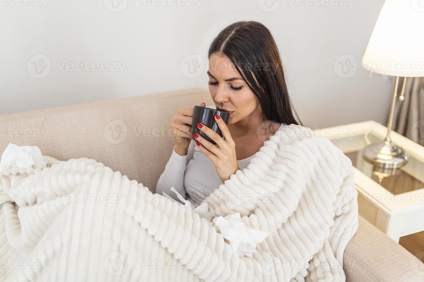 verkoudheid en griep. portret van ziek vrouw gevangen koud, gevoel ziek en drinken heet drank. detailopname van mooi ongezond meisje gedekt in deken afvegen neus. gezondheidszorg concept. foto