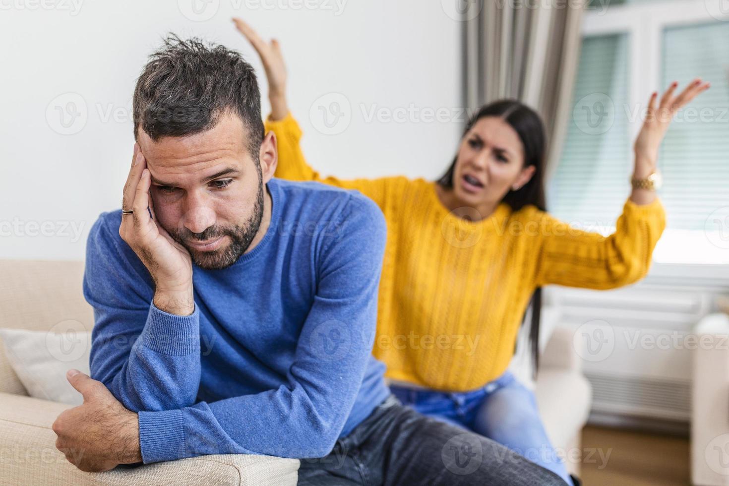 jong paar hebben argument - conflict, slecht verhoudingen. boos woede vrouw. boos jong paar zitten Aan bankstel in leven kamer hebben familie strijd of ruzie lijden van misverstand foto