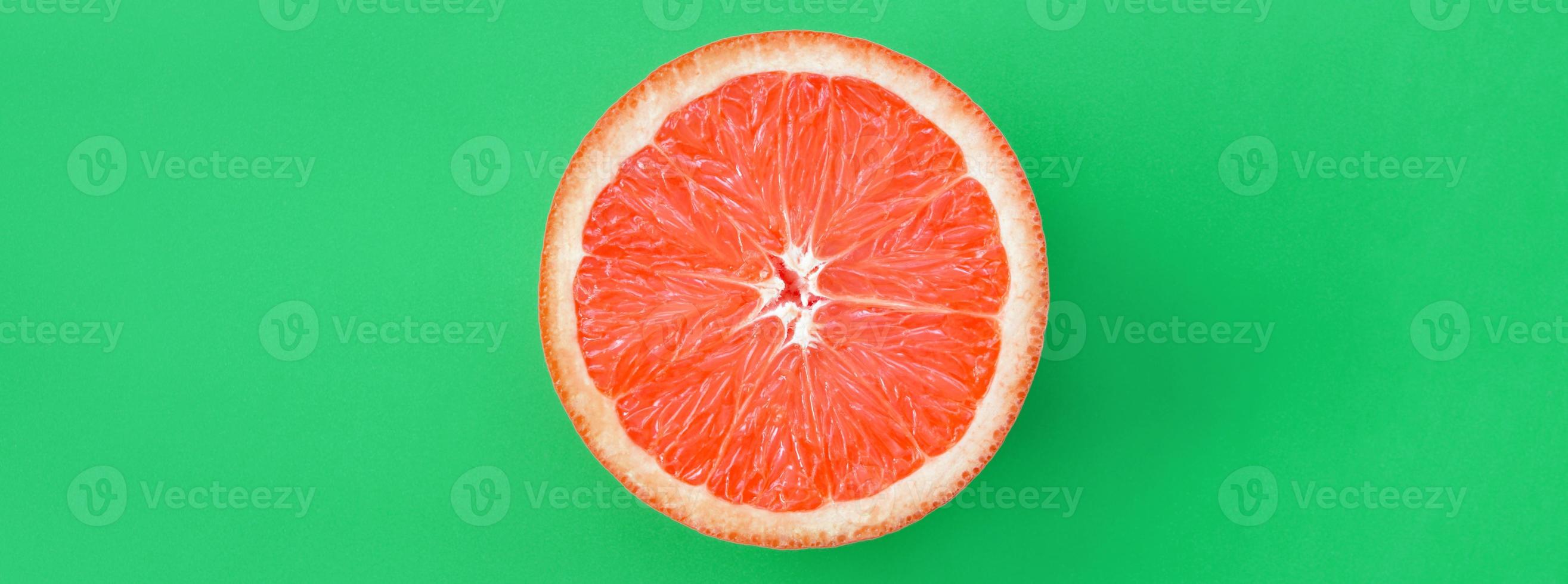 top visie van een een grapefruit plak Aan helder achtergrond in groen kleur. een verzadigd citrus structuur beeld foto