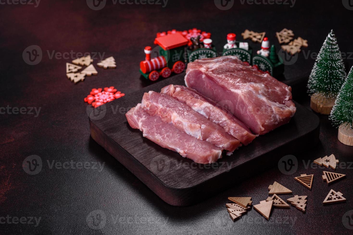 vers stuk van rauw varkensvlees met kruiden, zout en kruiden Aan een houten snijdend bord foto