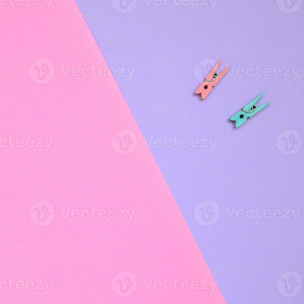 twee gekleurde houten haringen liggen Aan structuur achtergrond van mode pastel paars en roze kleuren papier in minimaal concept foto