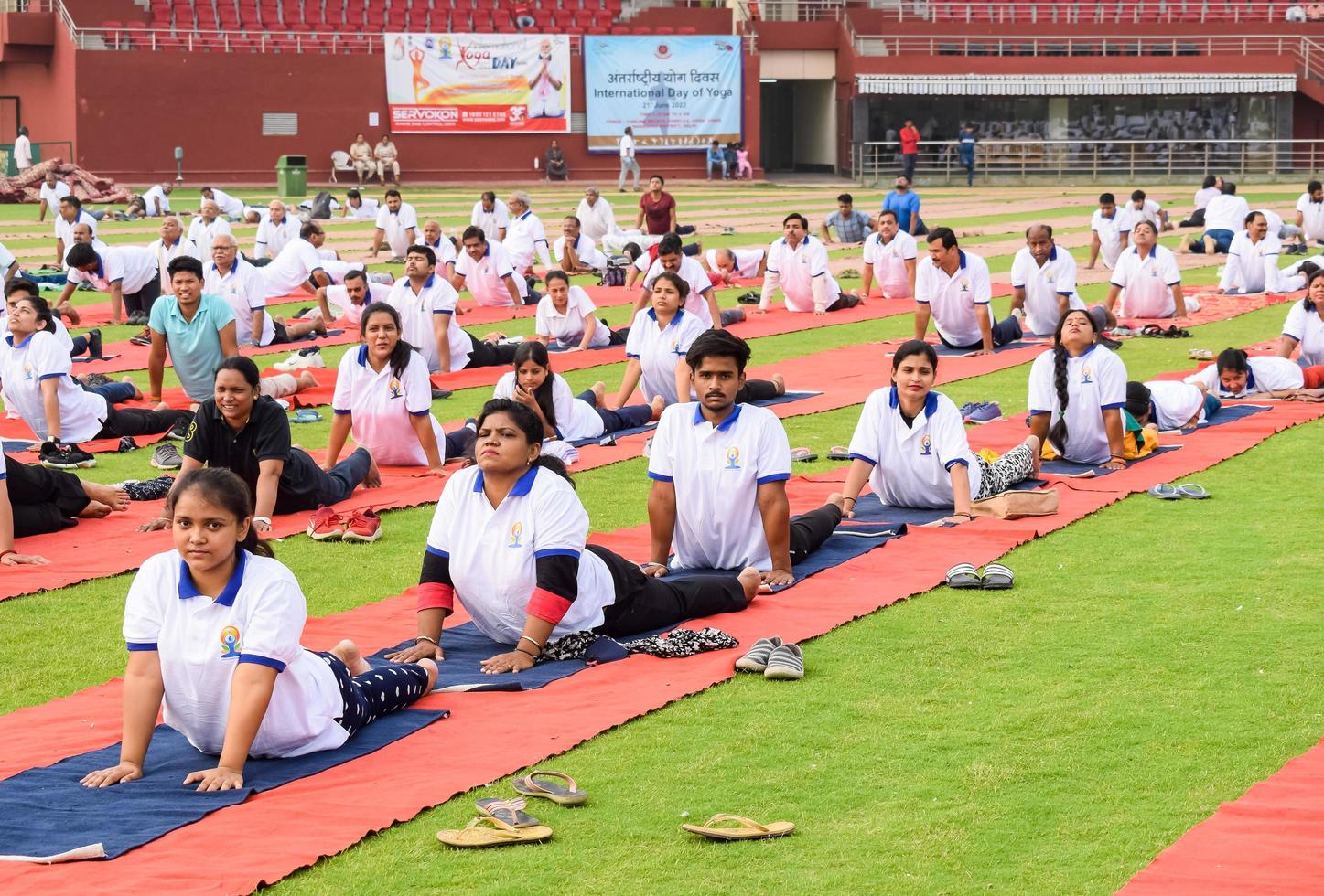 nieuw Delhi, Indië, juni 21 2022 - groep yoga oefening sessie voor mensen Bij Yamuna sport- complex in Delhi Aan Internationale yoga dag, groot groep van volwassenen Bijwonen yoga klasse in krekel stadion foto