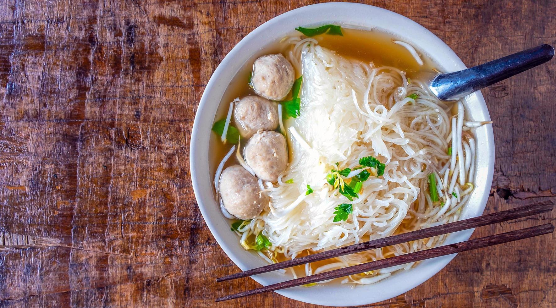 noodle en gehaktballen in een kom Aan een houten tafel foto