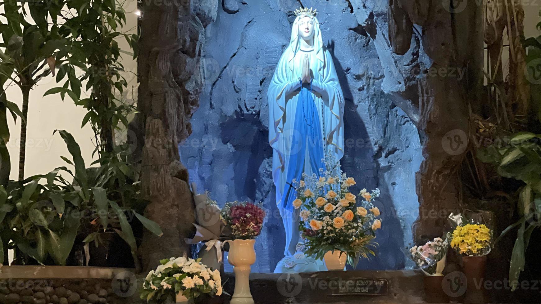 de grot van maagd Maria, standbeeld van maagd Maria in een rots grot kapel Katholiek kerk met tropisch vegetatie foto