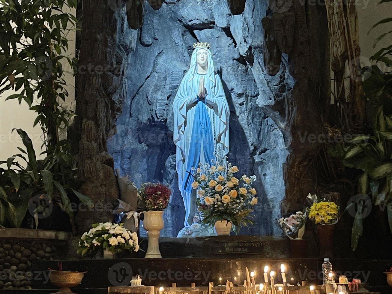 de grot van maagd Maria, standbeeld van maagd Maria in een rots grot kapel Katholiek kerk met tropisch vegetatie foto