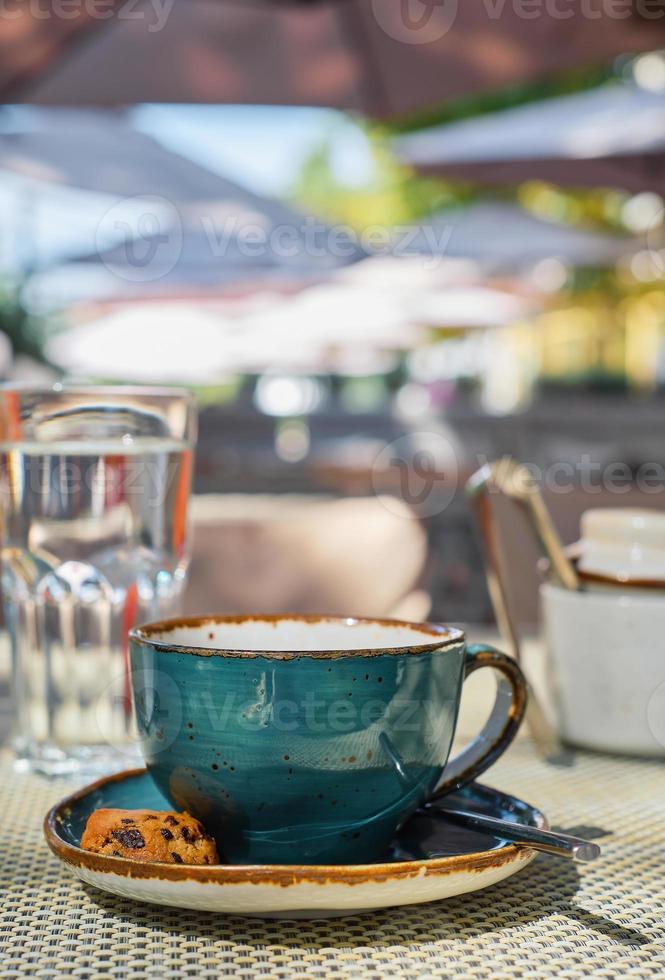 verticaal schot, een kop van espresso koffie, een glas van water en koekjes Aan de tafel, koffie breken tijd. detailopname, zonlicht en selectief focus, leeg ruimte, idee voor reclame of banier foto