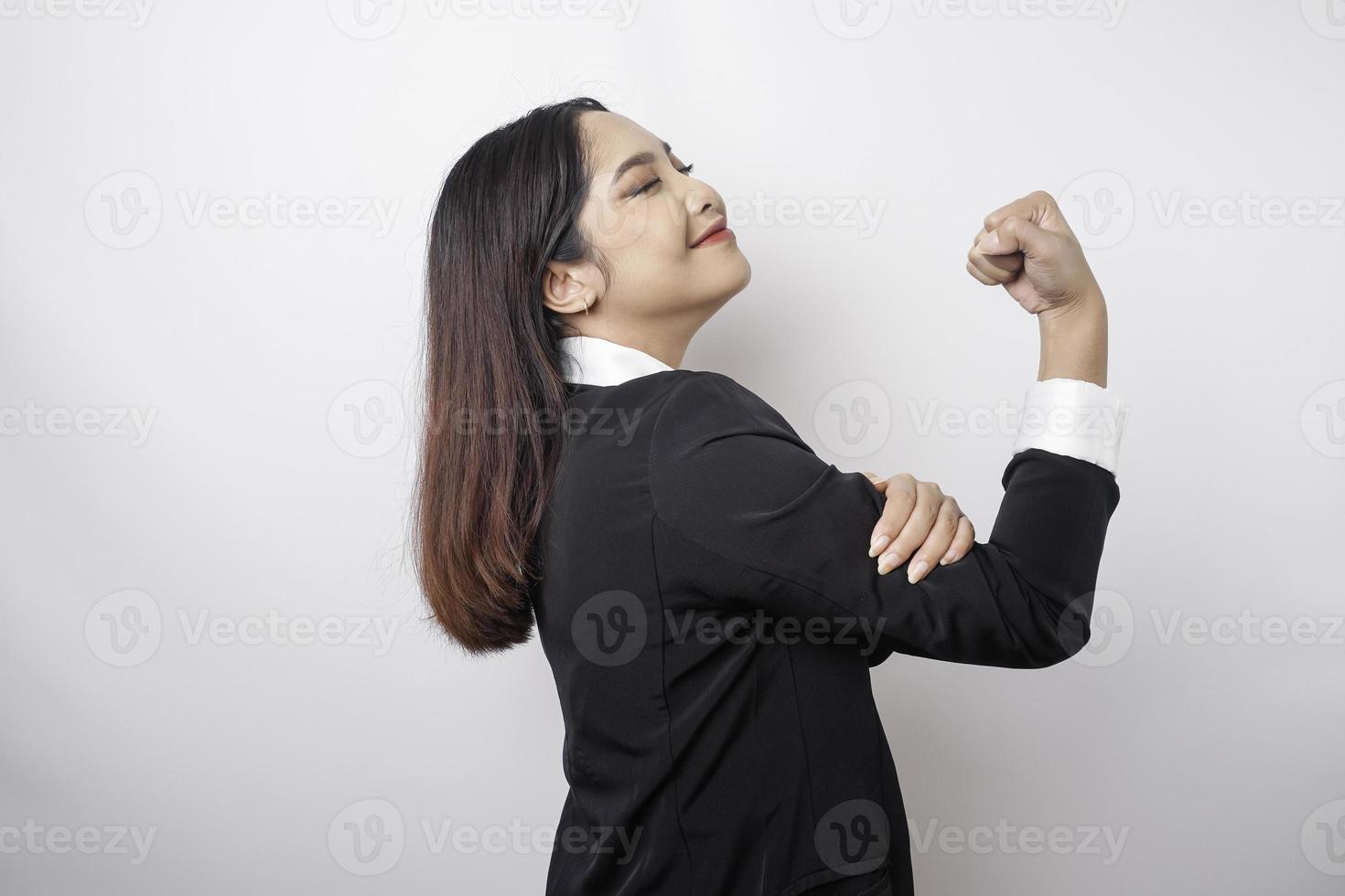 opgewonden Aziatisch bedrijf vrouw vervelend een zwart pak tonen sterk gebaar door hijs- haar armen en spieren glimlachen trots foto