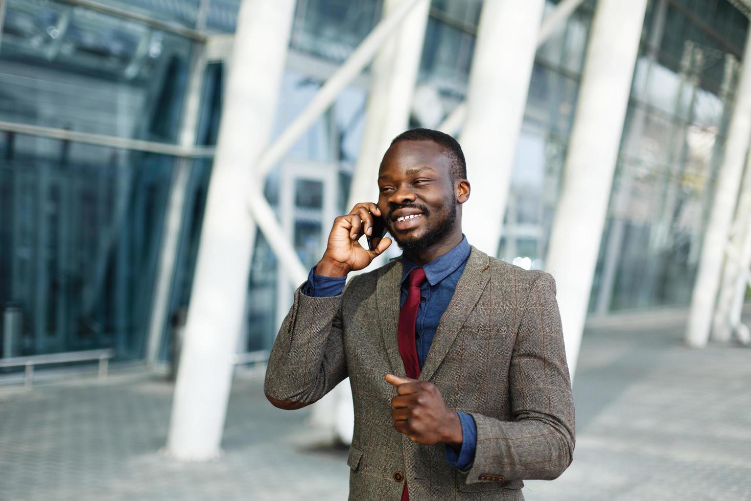stijlvolle Afro-Amerikaanse zwarte zakenman gesprekken op zijn smartphone foto