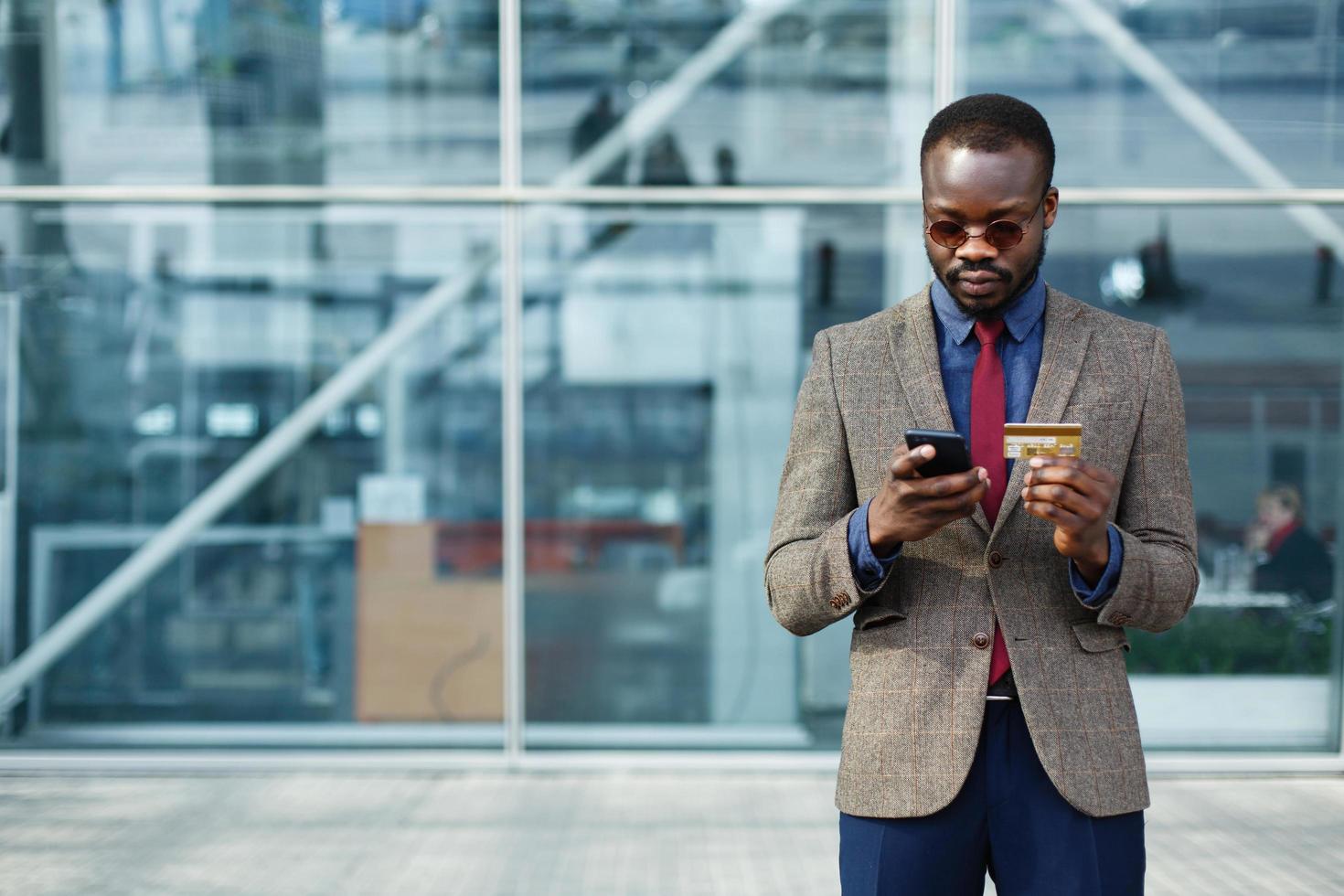 stijlvolle Afro-Amerikaanse zwarte zakenman typt informatie van zijn creditcard foto