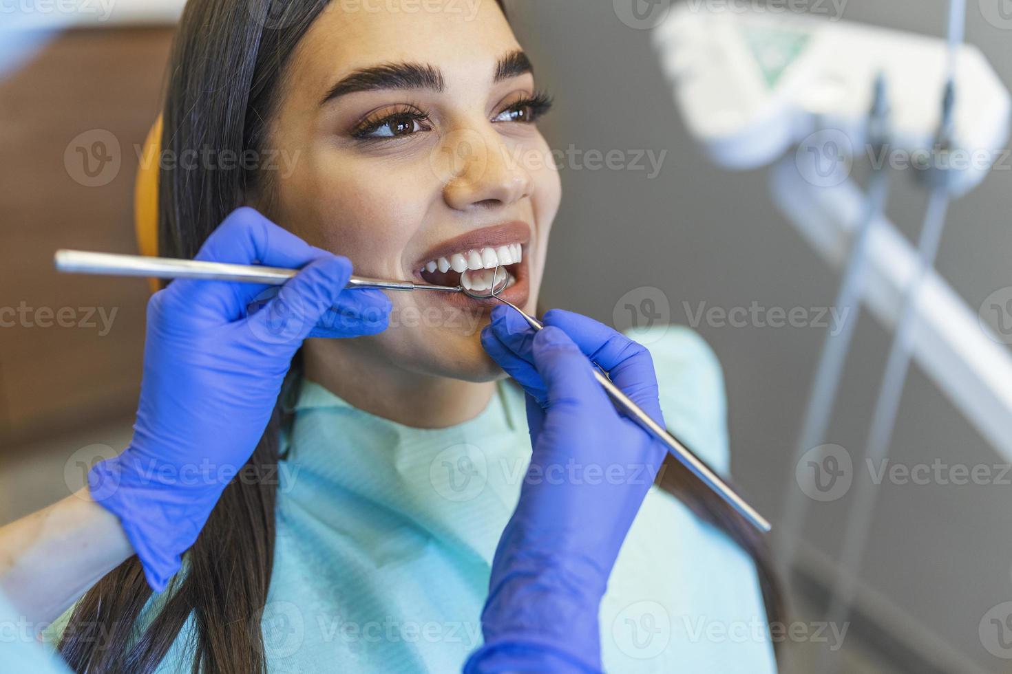 vrouw looks in de spiegel in tandarts stoel. patiënten tanden schaduw met monsters voor bleken behandeling. bekeken mondeling hygiëne. vrouw Bij de tandarts. foto