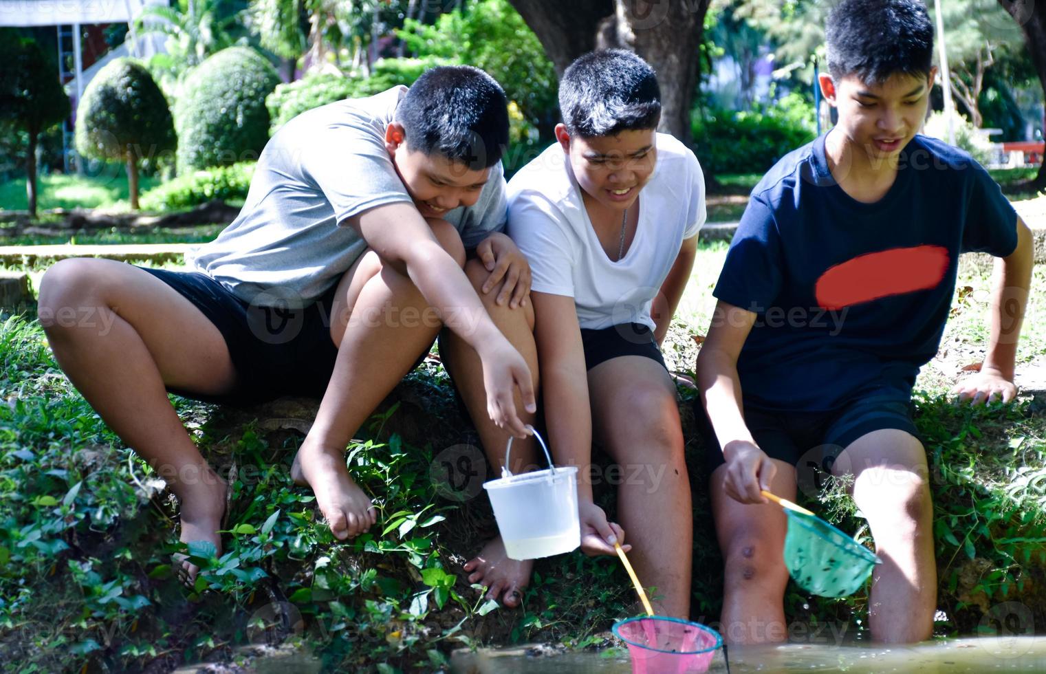 drie midden- school- jongens in zuidoosten Azië houden apparaten naar studie en onderzoeken de ecologie van de onder water ze leven in. ideeën voor aan het leren buiten de klas, zacht en selectief focus. foto