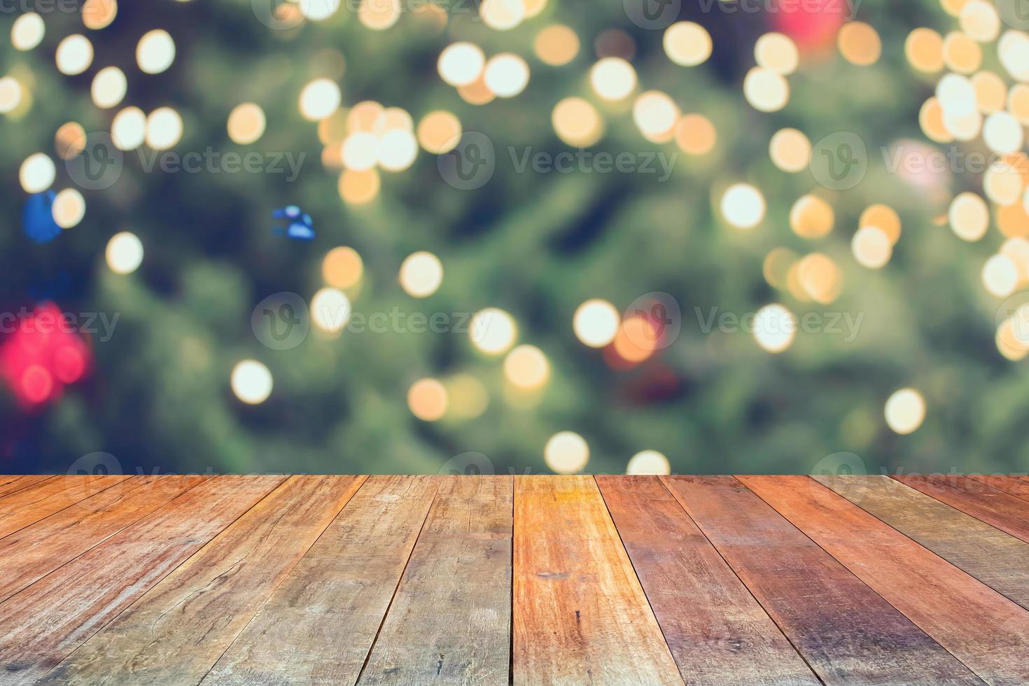 leeg hout tafel top met vervagen Kerstmis boom met bokeh licht achtergrond foto