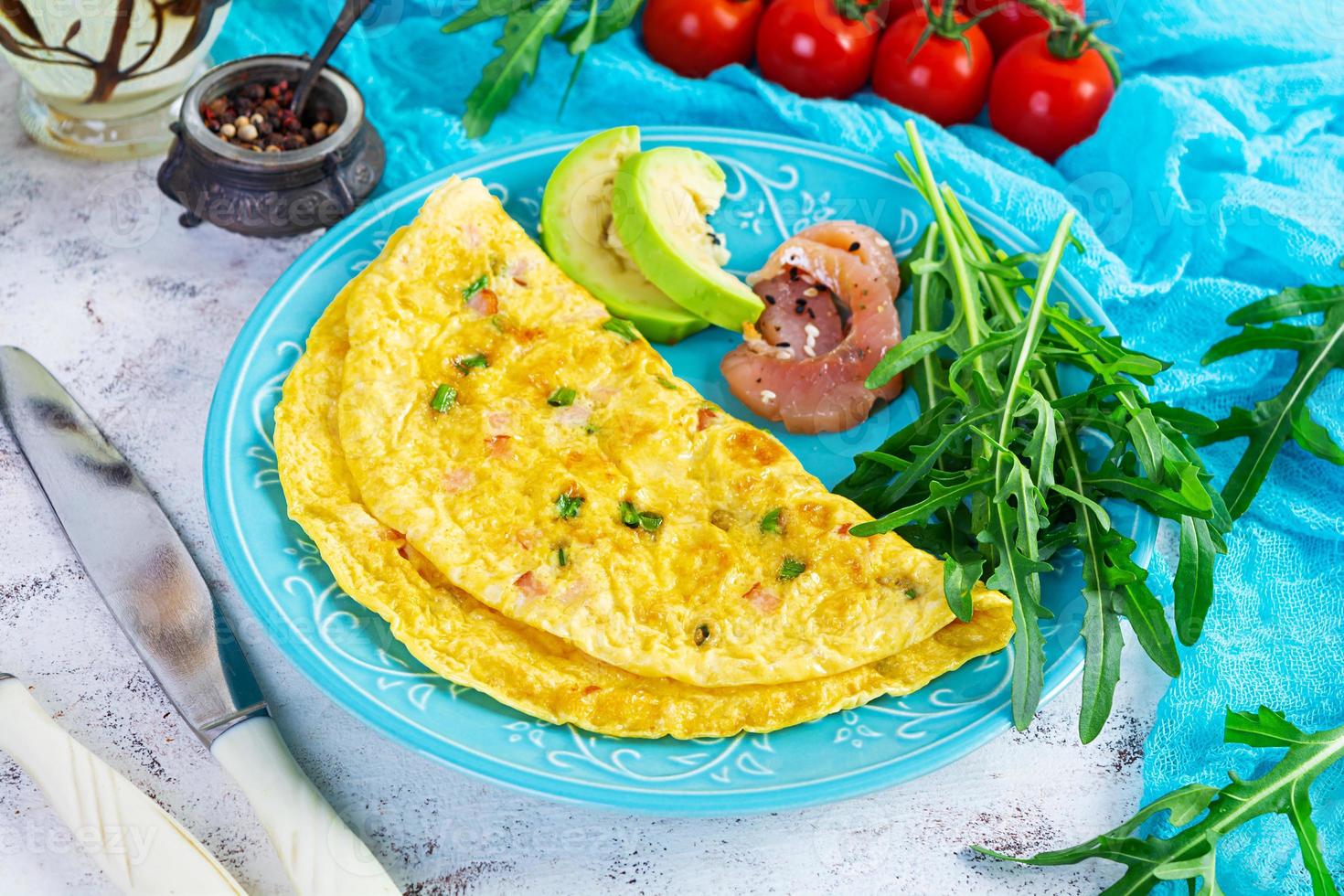 gebakken omelet met ham, ui en kruiden. ontbijt met door elkaar gegooid eieren foto