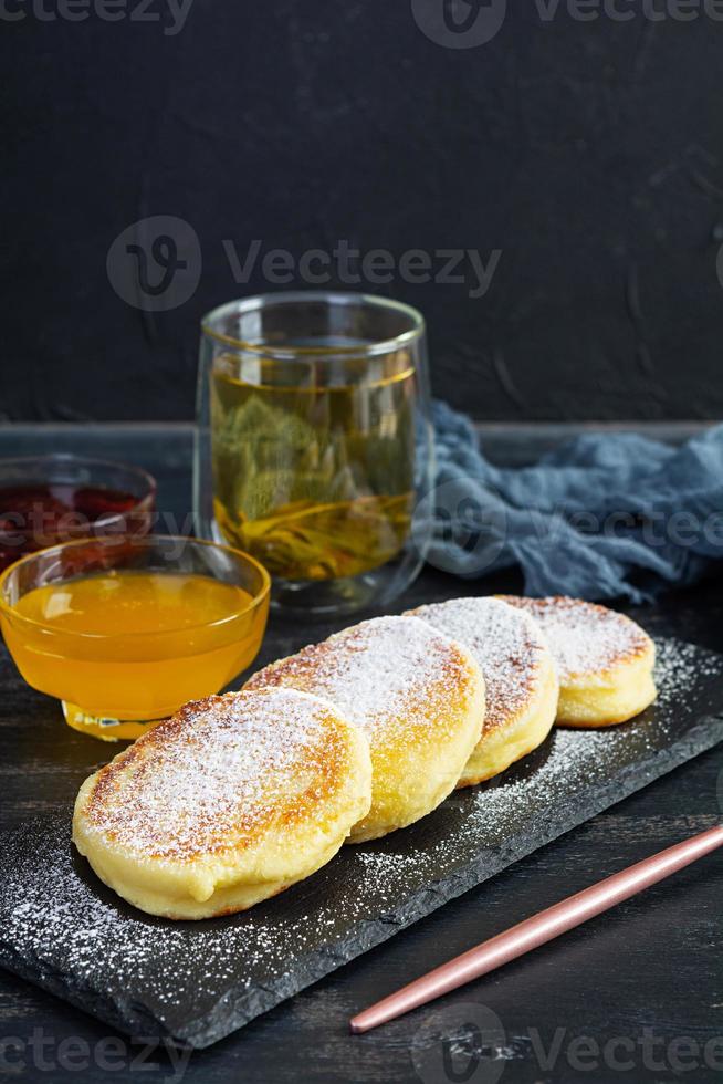 heerlijk eigengemaakt syrniki met aardbei jam en honing. traditioneel Russisch schotel syrniki foto
