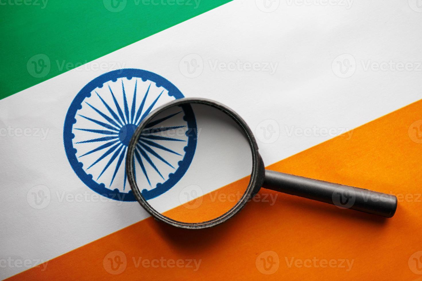 Indisch vlag op zoek door een vergroten glas. totaal toezicht van de land Indisch. de concept van verborgen gevaren en controle over- de land foto