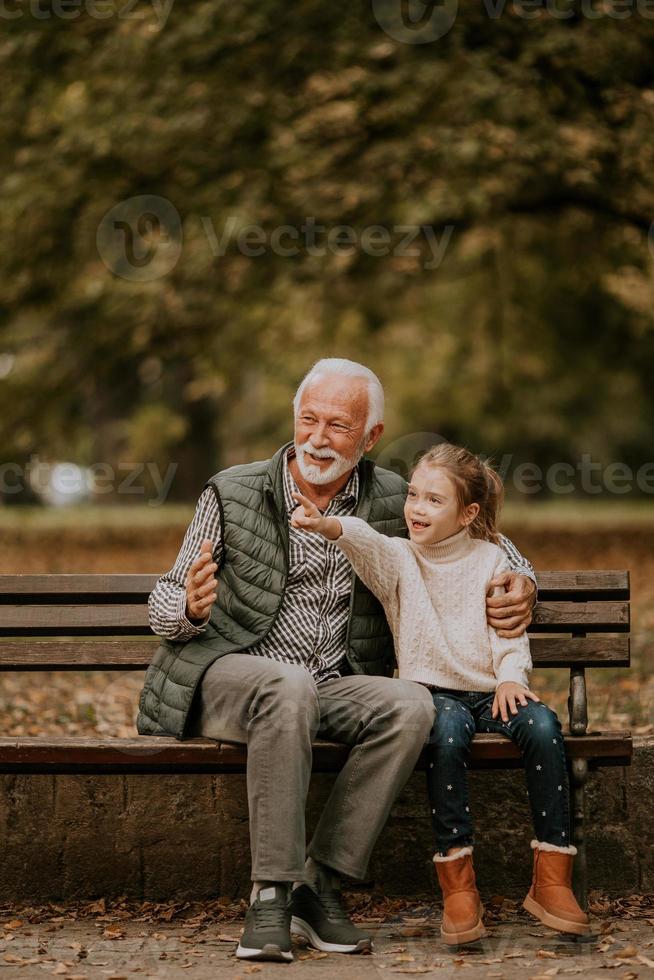 opa uitgeven tijd met zijn kleindochter Aan bank in park Aan herfst dag foto