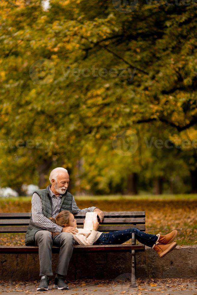 opa uitgeven tijd met zijn kleindochter Aan bank in park Aan herfst dag foto