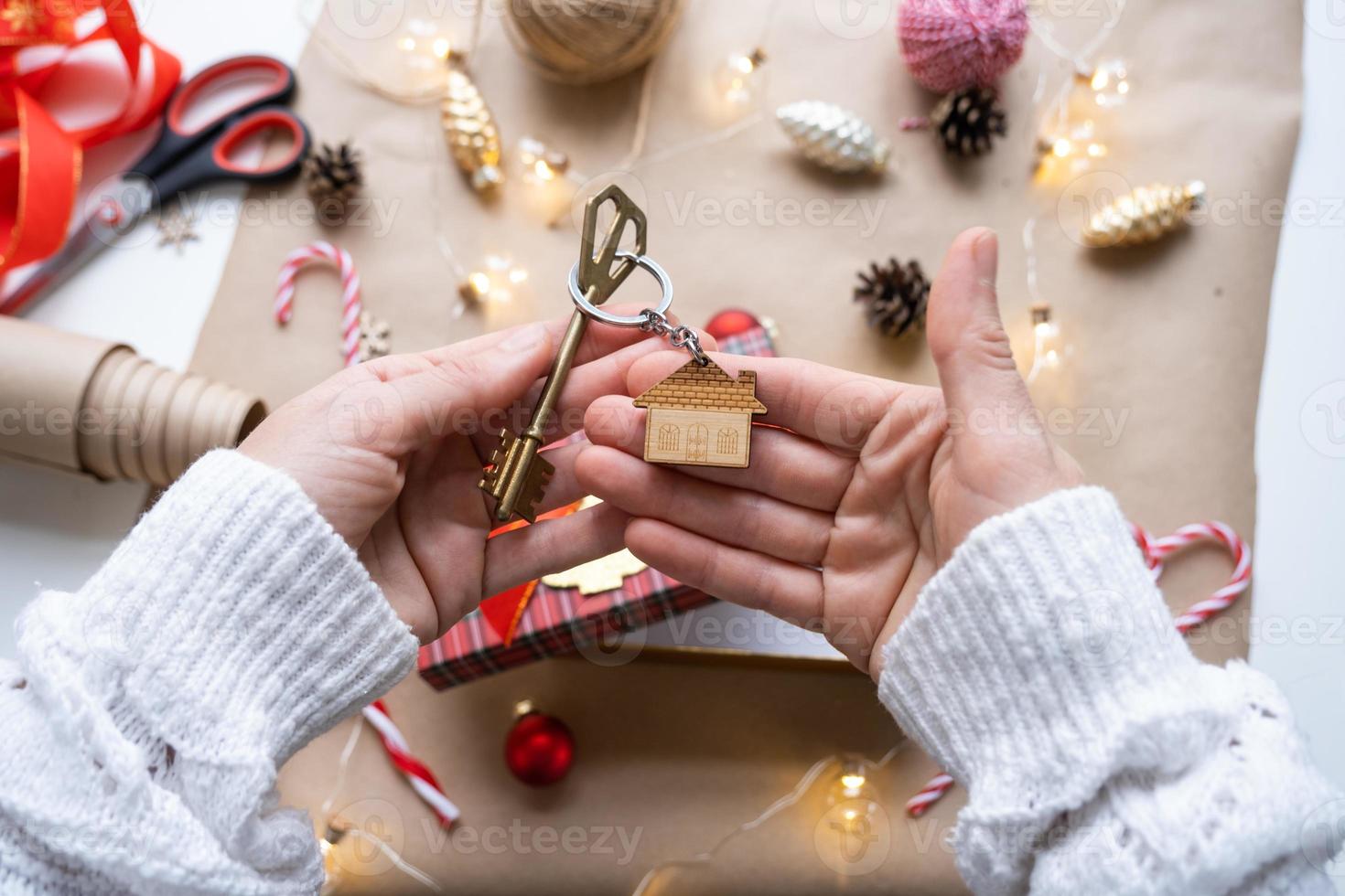 sleutel naar huis met sleutelhanger Aan knus huis in geschenk doos met Kerstmis decor verpakking. pak Cadeau voor nieuw jaar, kerstmis. gebouw, projecteren, in beweging naar nieuw huis, hypotheek, huur, aankoop echt landgoed foto