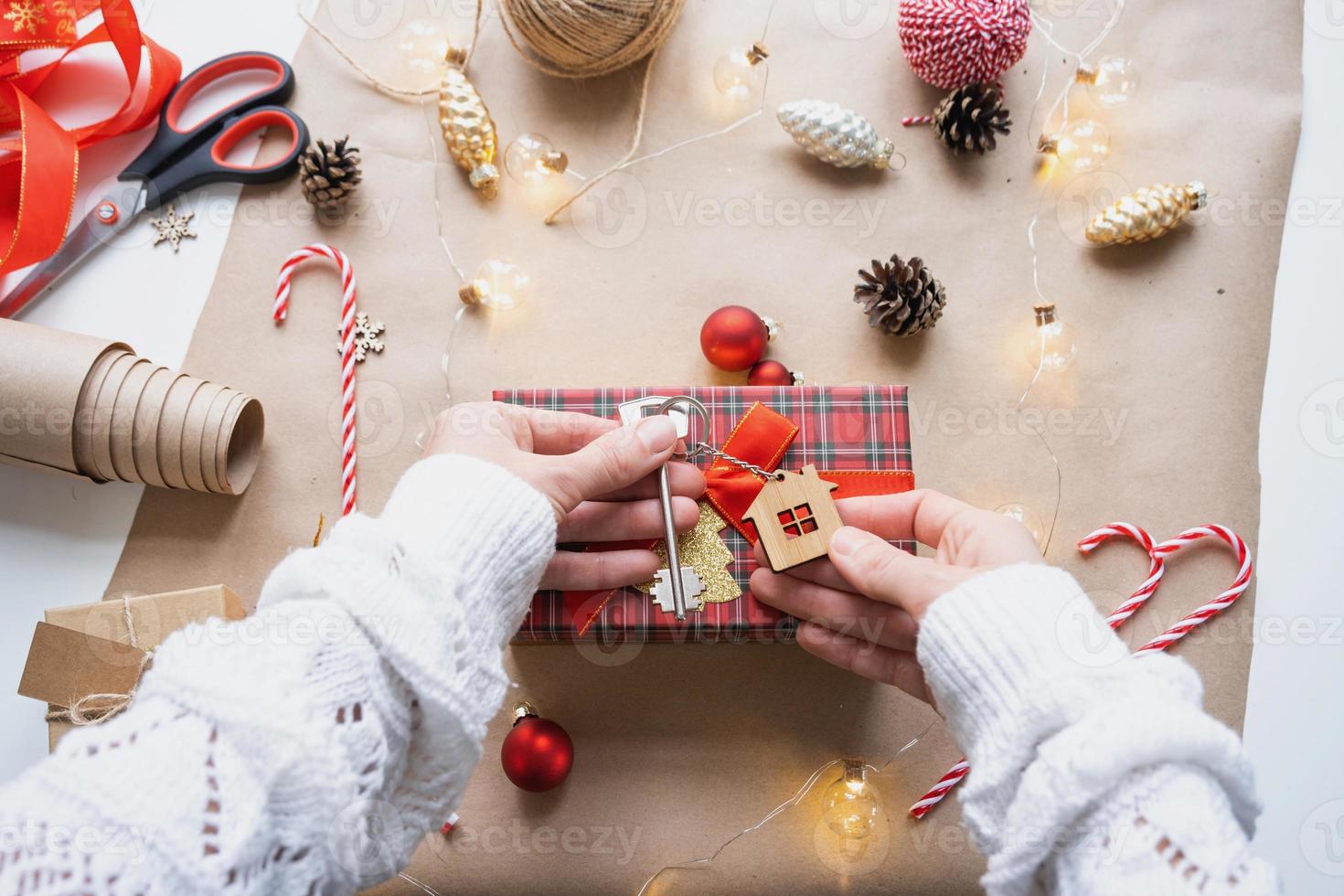 sleutel naar huis met sleutelhanger Aan knus huis in geschenk doos met Kerstmis decor verpakking. pak Cadeau voor nieuw jaar, kerstmis. gebouw, projecteren, in beweging naar nieuw huis, hypotheek, huur, aankoop echt landgoed foto