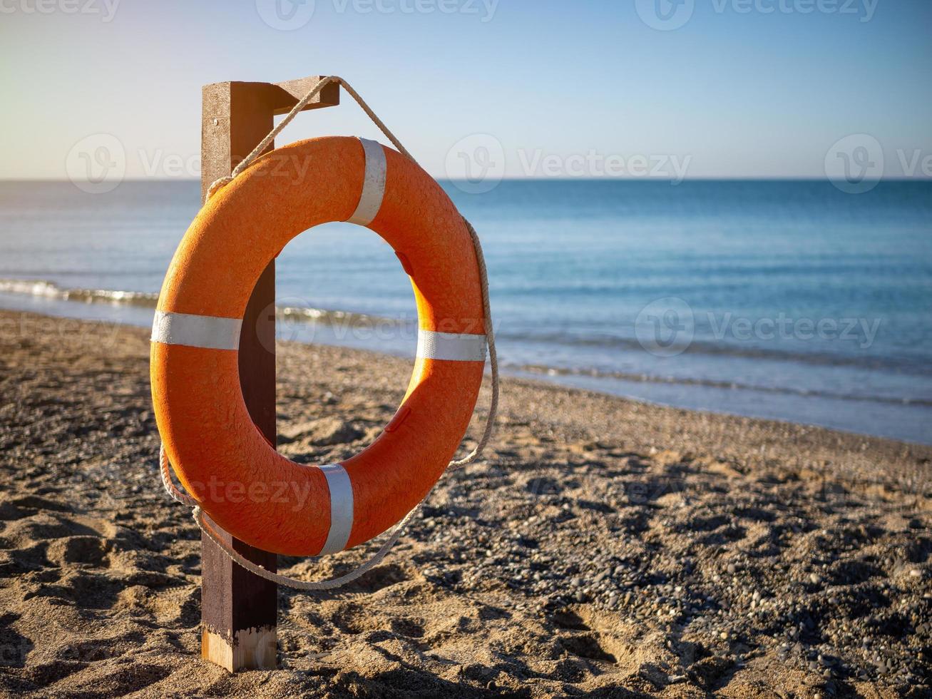 helder oranje reddingsboei Aan een zanderig strand Aan een zonnig zomer dag. foto