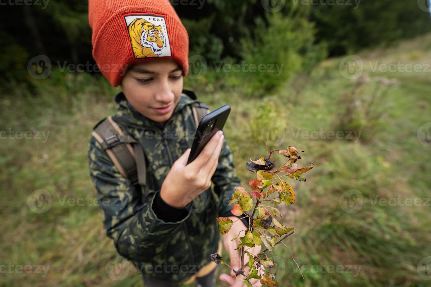 jongen maken een foto van rups- Aan een blad. studie van flora en fauna.