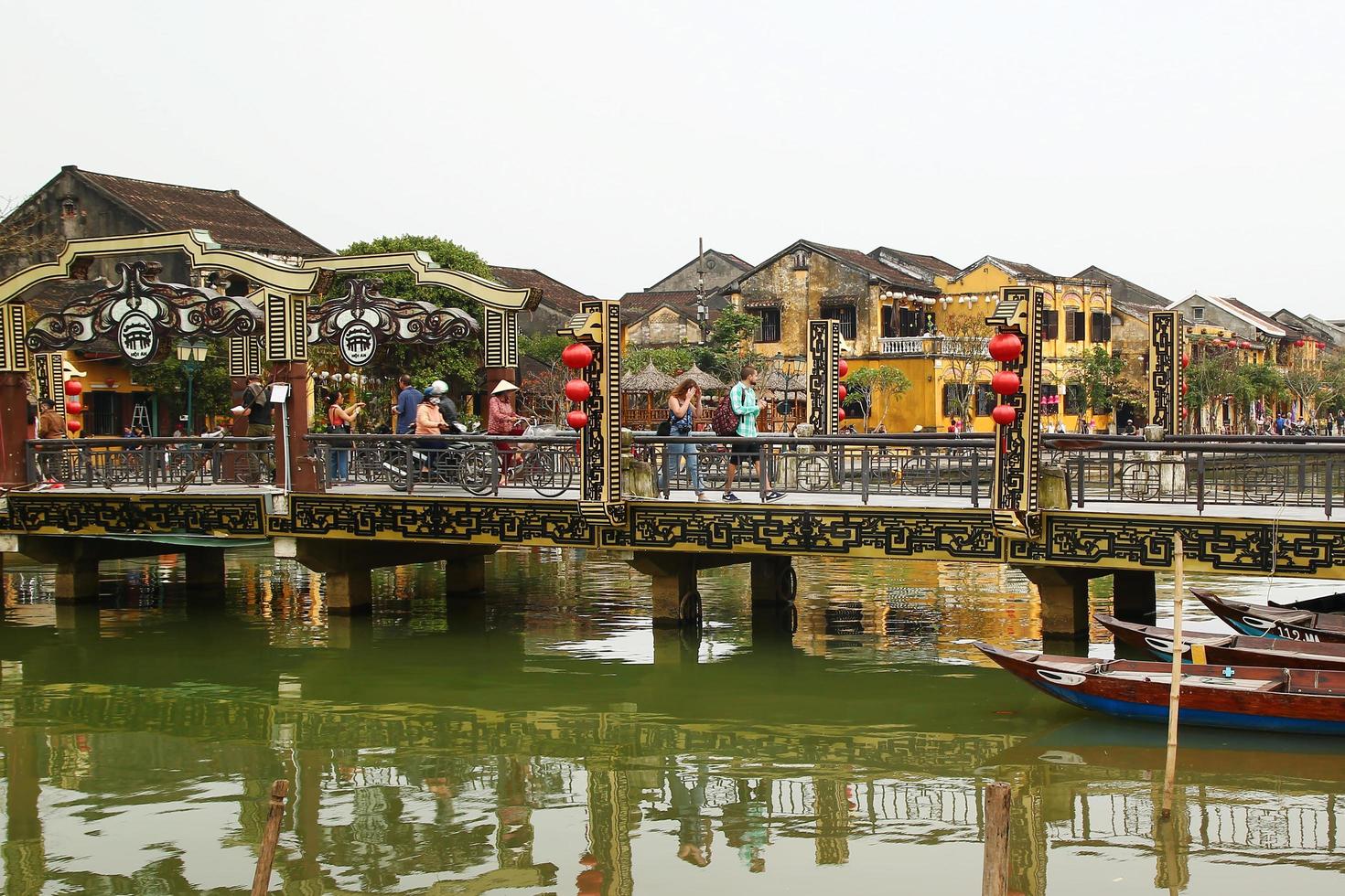 Hoi een, Vietnam - februari 12, 2018. brug aan de overkant naar de do bon rivier- met toeristen en huiselijk mensen Aan een achtergrond van historisch oud geel gebouwen. foto