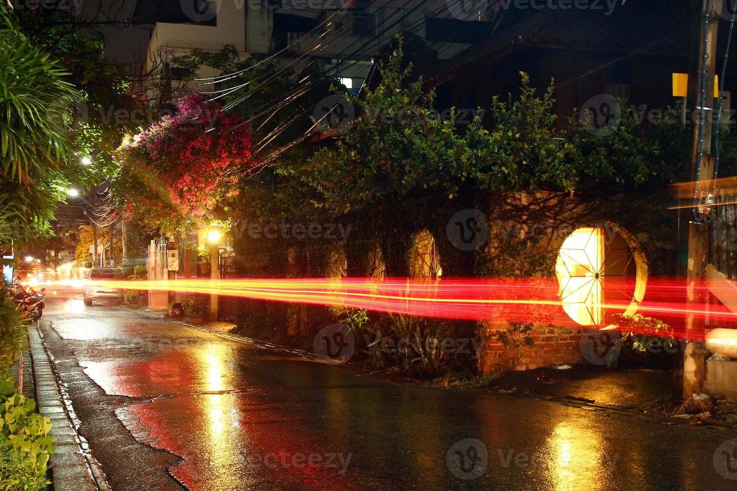 visie Aan een nacht straat van stad met lantaarn en in beweging vervoer in een regenachtig het weer. lang blootstelling. Chiang mei, Thailand. foto