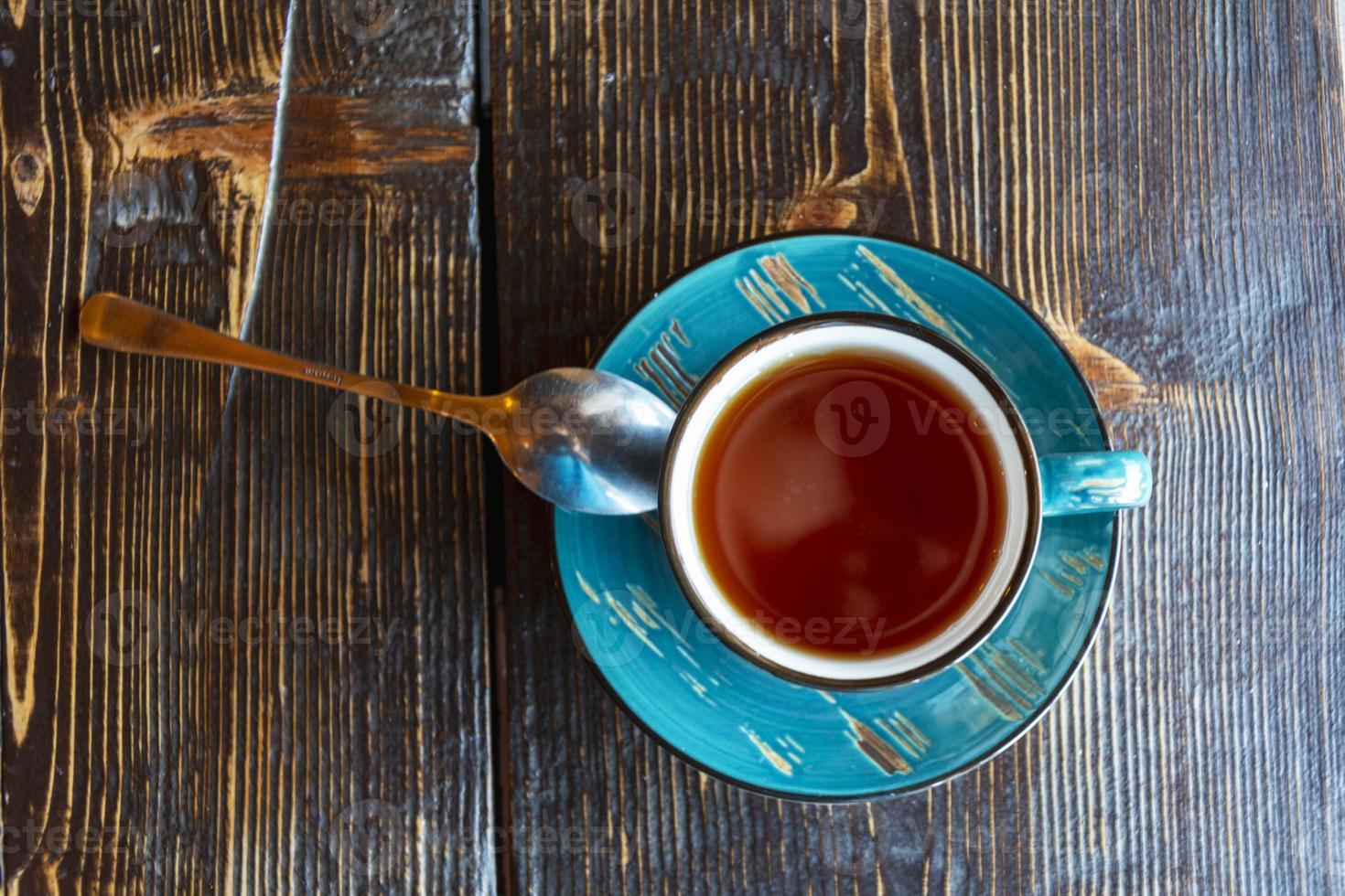 een kop van thee, een schotel en een theelepel Aan een ruw houten tafel in een cafe, brunch. vers thee, kalm. top visie foto