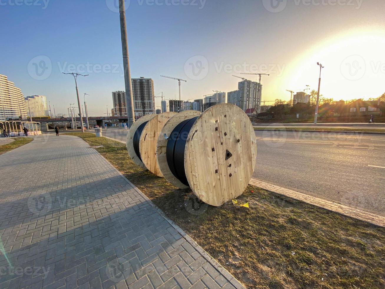 ronde houten strengen met elektriciteit kabel. de kabel is wond Aan een groot, houten spoel. bouw plaats, kabel houdende ondergronds naar voorzien de Oppervlakte met elektriciteit foto