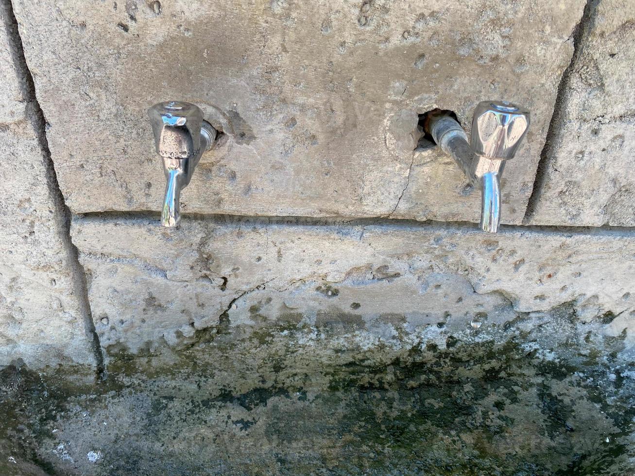 drie kranen van welke water stromen. de water is schoon en Doorzichtig voor drinken. kranen gemaakt in een steen muur foto